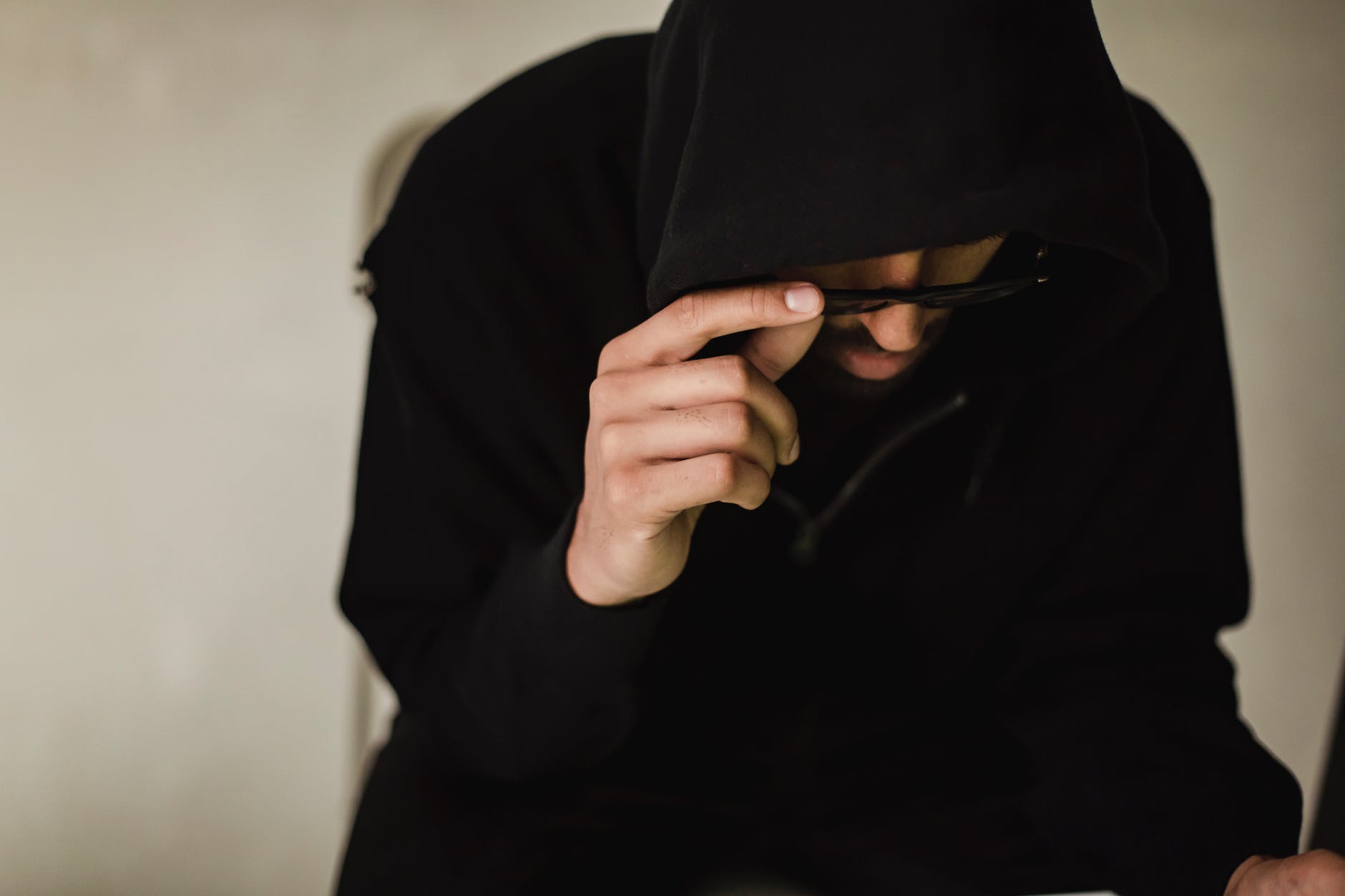 7 طرق للنصب والاحتيال.. تجنب الوقوع فيها crop hacker in black hoodie lowering eyeglasses